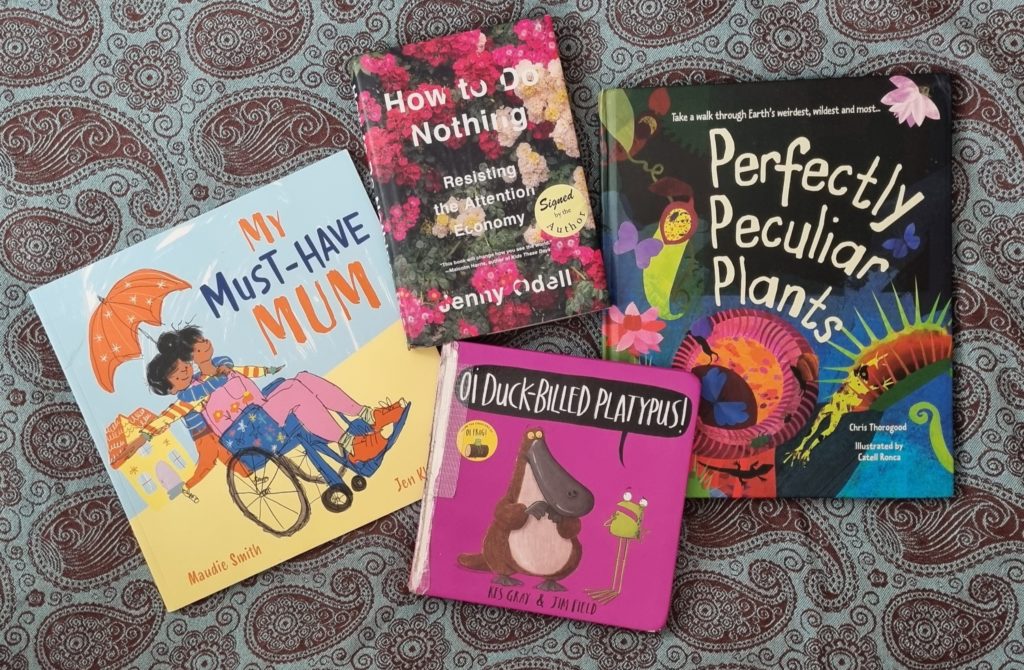 Four books laid out on a cloth: How to Do Nothing; My Must-Have Mum; Perfectly Peculiar Plants; and Oi Duck-Billed Platypus!
